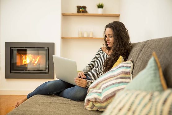 Frau auf Couch vor Ofen